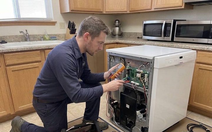 Technician metering a dishwasher control board with the side panel open