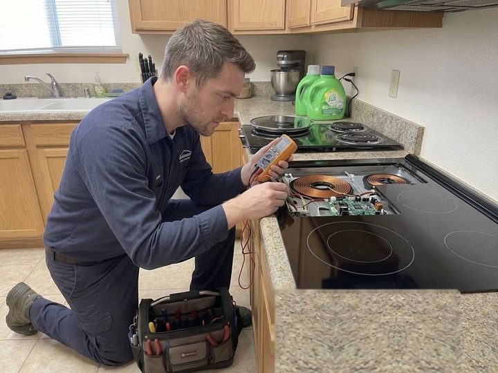 Technician testing induction cooktop coils with a multimeter